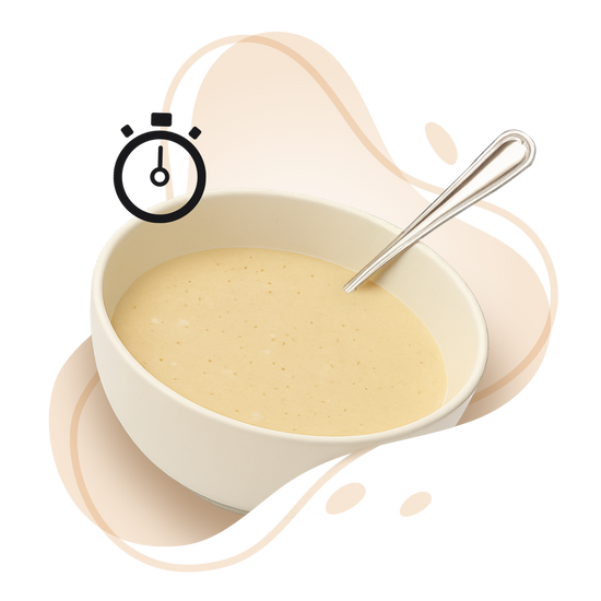 White bowl with creamy soup and a spoon on a white background