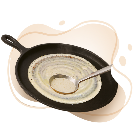 Skillet with crepe being made and a ladle on a white background